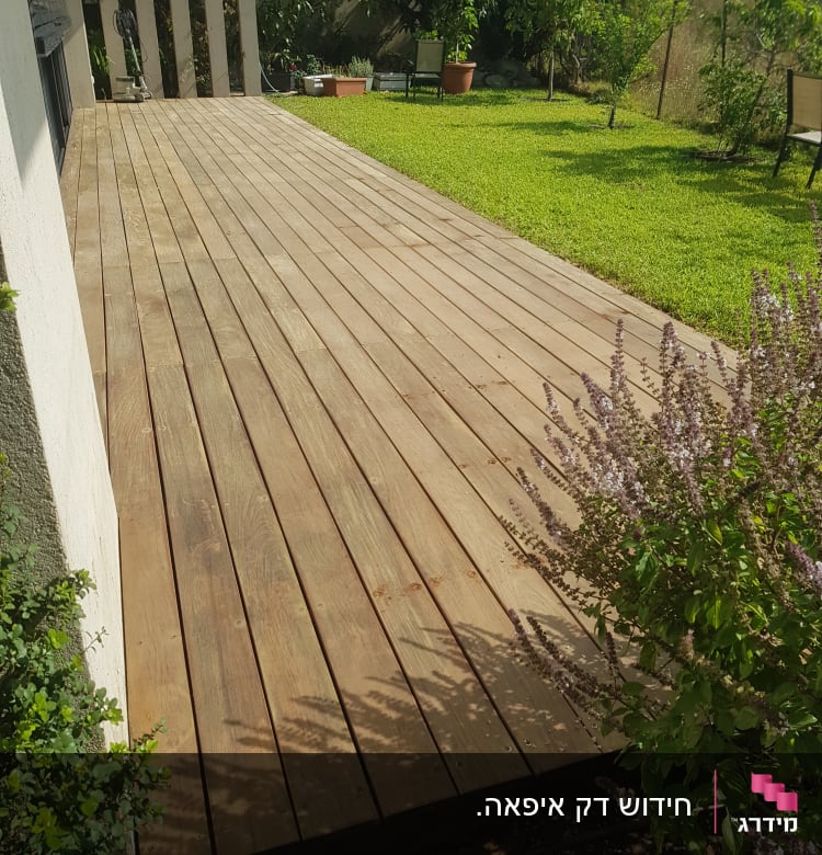 דק עץ בגינה עם צמחייה מסביב